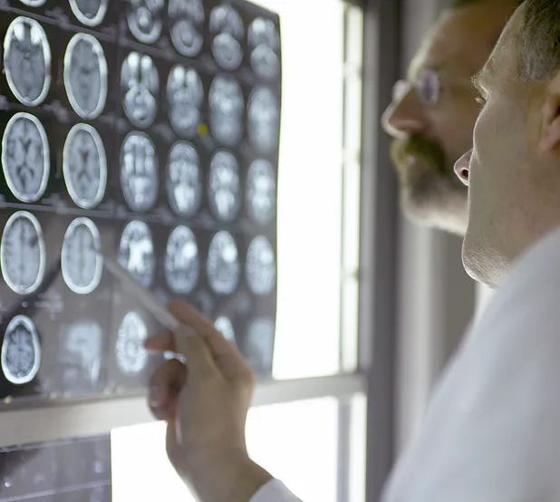 Two men looking at a display of mri scans.