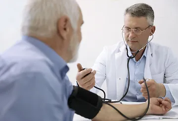 A doctor is examining an older man 's blood pressure.