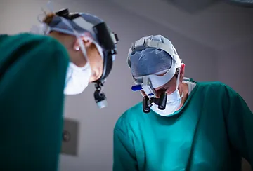 Two doctors wearing surgical masks and helmets.